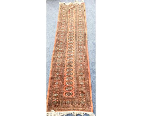 VINTAGE BOHARA WOOLLEN RUNNERwith medallions on faded red ground, with fringing, 82 x 296cm; with a Turkish woollen rug, on a