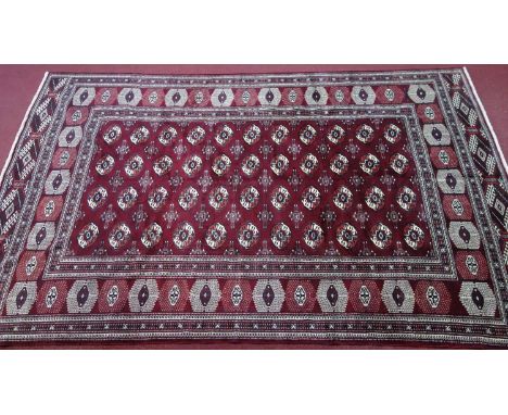 A Northeast Turkoman carpet, repeating stylised all over Tekkeh motifs on a rouge field, complemented by a stylised repeating
