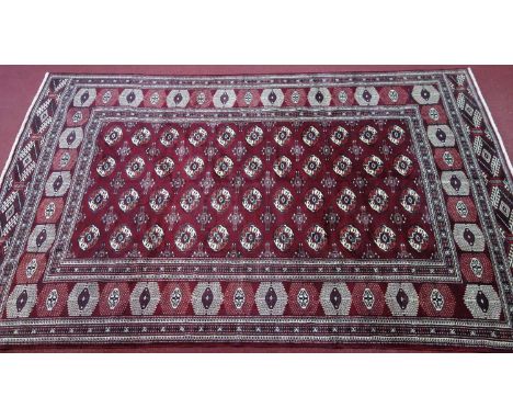 A Northeast Turkoman carpet, repeating stylised all over Tekkeh motifs on a rouge field, complemented by a stylised repeating