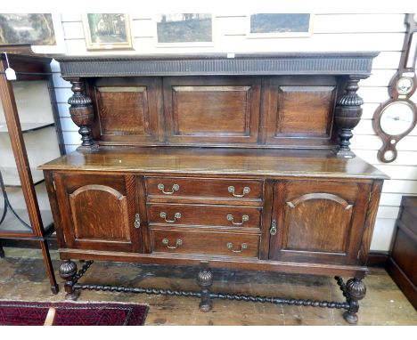 Jacobean style oak sideboard, the fluted and fielded panel back with carved cup and over supports, three central drawers flan