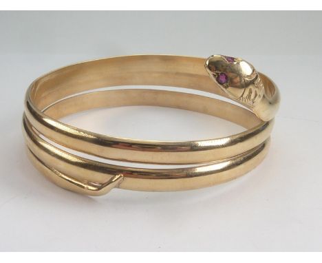 9ct gold bangle modelled as a serpent with three plain coils and ruby eyes.Weight:67g 