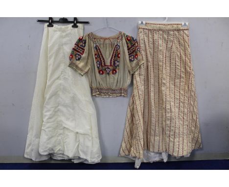 Vintage peasant style muslin blouse with polychrome embroidered floral decoration and smocked hem; a cream and red striped se