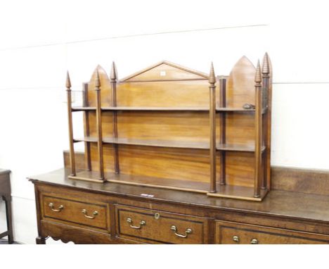 An early 19th century 'Strawberry Hill' mahogany set of three hanging wall shelves supported on reeded columns with fir cone 