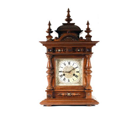 An Edwardian mantle clock in a baroque-style walnut case, h. 56 cm Face with staining, case with losses and wear commensurate