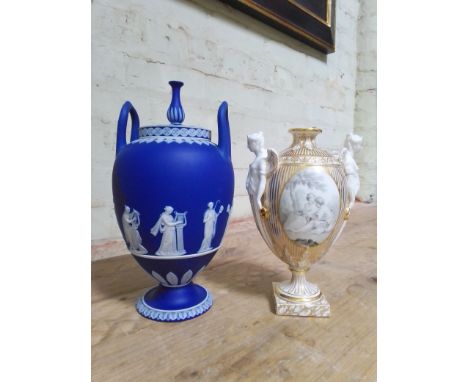 Two porcelain urns comprising a Wedgwood Jasper ware twin handled and lidded pedestal urn decorated with classical figures an