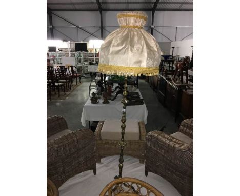 A patinated brass effect standard lamp with shade