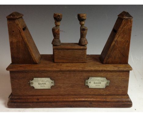 A Victorian folk art oak automaton money box, each primitively carved pivoting figure tilting to deliver a coin to an apertur