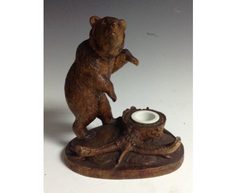 A Black Forest novelty inkwell, carved with a bear, on hind legs, traversing the woodland floor, 18cm high, early 20th centur