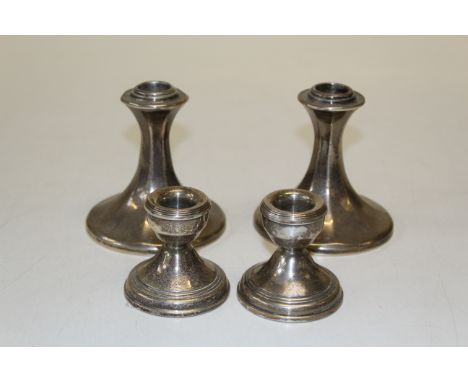 Two pairs of silver dwarf candlesticks, the first of outswept faceted form, by William Comyns, London, 1908, the second with 