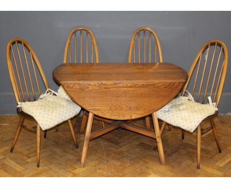 An Ercol light elm drop flap dining table, the oval top raised on fluted splayed square supports, together with a set of four