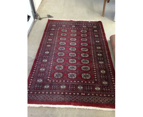 A vintage red patterned wool rug/carpet. Approx 190 x 127cm - fringed.