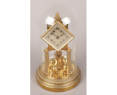 A German brass torsion clock under glass dome and diamond shape dial.  