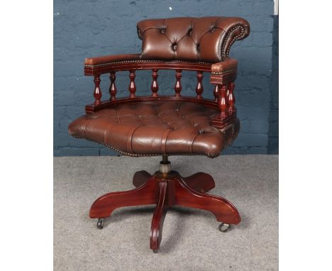 A brown leatherette deep button swivel office chair.  Wear to arms.