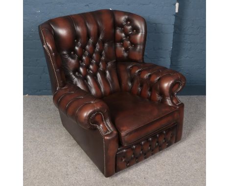 A brown leatherette deep button wing back arm chair.  