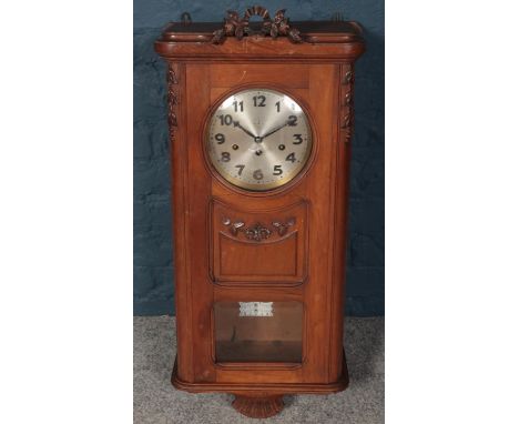 An Edwardian carved mahogany 8 day wall clock. Hour chiming on Westminster.  Floral finial loose.