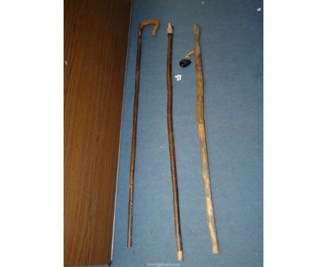 A Shepherd's crook, thumb stick with attached cowbell and another stick with carved head of a sheep dog.