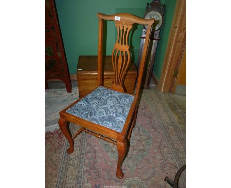 A set of four matching light Oak framed Chairs having shaped top rails, fret worked splats and drop in seats upholstered in b