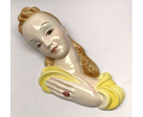 A 20th century American Goldscheider Art Deco wall mask, modelled as a blonde haired female in yellow dress, with printed mar