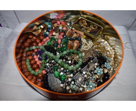 A tin containing a selection of costume jewellery including earrings, spoon bangle, beads etc