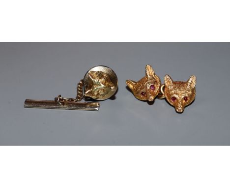 A single 9ct gold cufflink modelled as a pair of fox masks with ruby-set eyes and a 14k single fox mask dress stud.