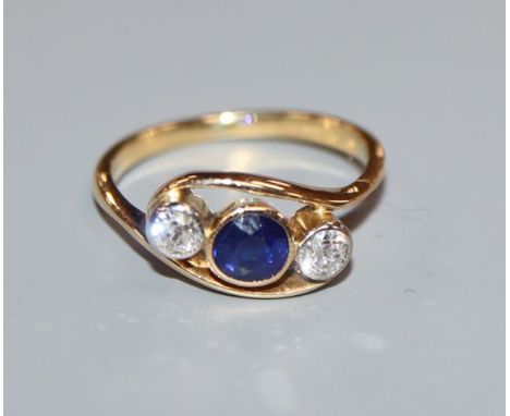 A modern 18ct gold three stone diamond and sapphire crossover ring, size K.