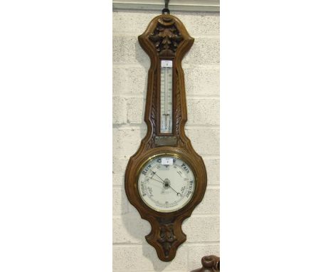 A late-Victorian carved oak aneroid barometer/thermometer by Solanson &amp; Co, Bristol, 92cm high.