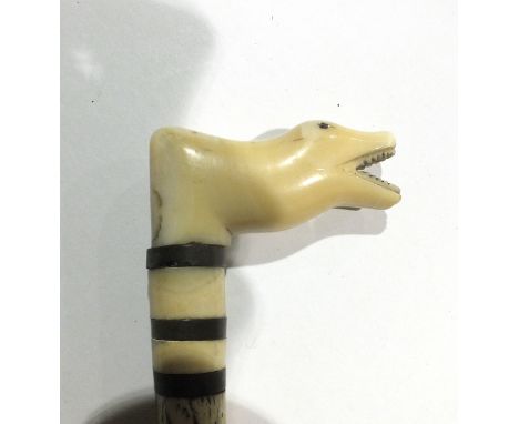 A bone walking stick with carved animal's head handle, 69cm long.