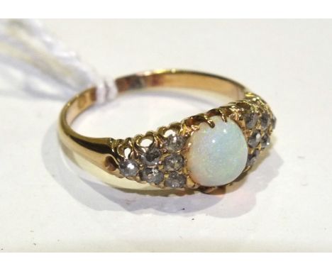 A Victorian opal and diamond ring set an oval opal between two triangular clusters, each of six old brilliant-cut diamonds, i