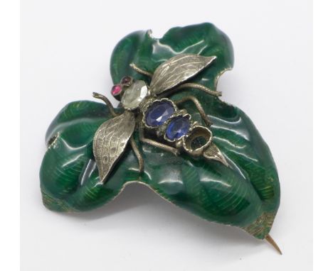 A ruby, sapphire and diamond set insect brooch set on an enamelled green leaf, enamel a/f and lacking one sapphire, 42mm x 42