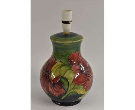 A Moorcroft Hibiscus pattern baluster shaped table lamp, tube lined  with large flowerheads in red, on a green ground, 26cm h