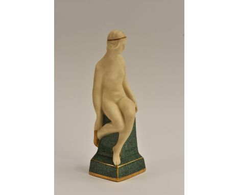 A Royal Worcester bisque figure, The Golden Slippers, female nude seated on a moss green pillar, a golden circlet in her hair