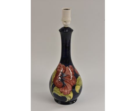 A Moorcroft Hibiscus pattern table lamp, tube lined with large flowerheads in tones of yellow and red, on a cobalt blue groun