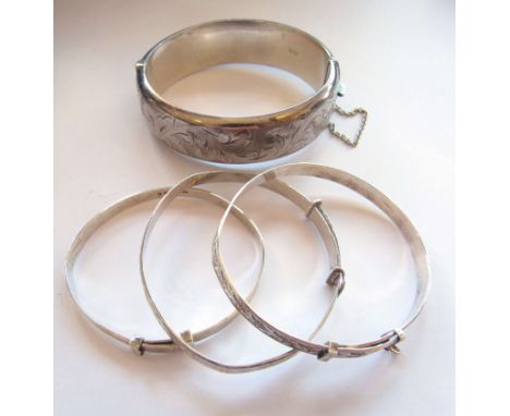 A silver wax filled engraved stiff hinge bangle, two silver christening bracelets and another stamped sterling, 64.6g