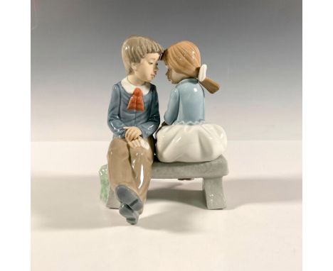 A boy and girl sitting on a bench about to begin the journey of love. Glossy finish. Nao by Lladro backstamp. Artist: Vicente