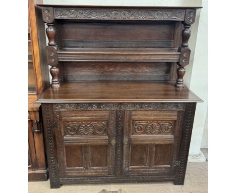 A 17th century style court cupboard with a carved frieze and shelf, the base with two cupboards on stiles, 144cm wide x 177cm