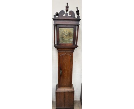 A 19th century oak longcase clock with a shaped top and turned finials, with an arched trunk door, box base and plinth, the 2