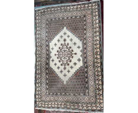 A rug with a cream ground and a central pointed medallion within multiple guard stripes 295 x 195cm