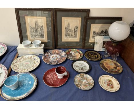 A cranberry and clear glass oil lamp together with assorted collectors plates, prints etc 