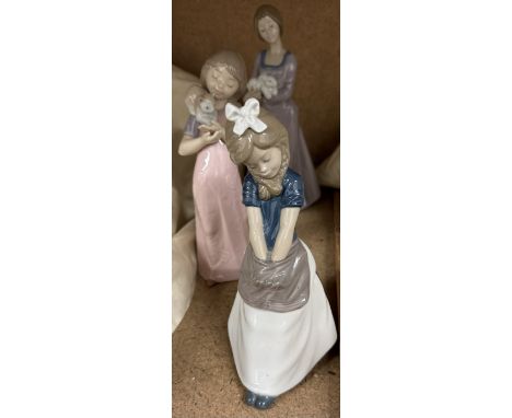 Three Nao figures of young girls, one with a rabbit, the other a kitten and the third with her hands in her apron