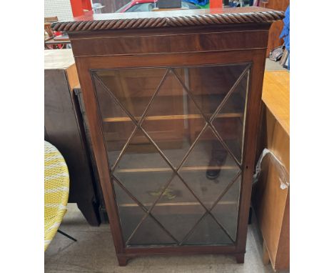 A mahogany display cabinet with a gadrooned top and glazed door with glazing bars on bracket feet