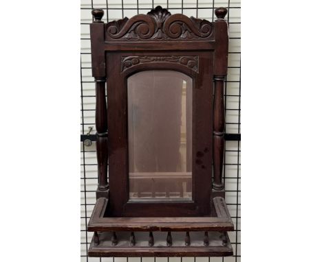 A mahogany wall mirror with a carved cresting and a galleried shelf 