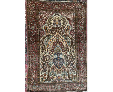 A Persian prayer rug with a central arched medallion decorated with a vase and flowers and leaves to a scrolling border and m