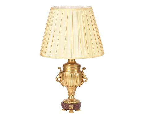 A French gilt metal table lamp, early 20th century and later fitted for electricity, the urn-and-cover body above a rouge gri