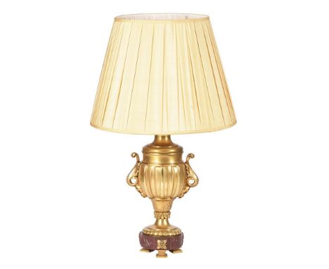 A French gilt metal table lamp, early 20th century and later fitted for electricity, the urn-and-cover body above a rouge gri