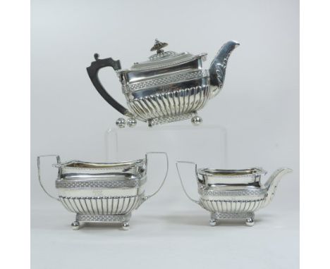 A George III silver three piece tea service, of half gadrooned rectangular shape, with a shell decorated border and basketwea