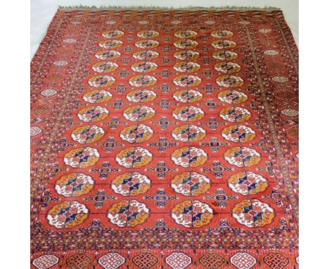 A Bokhara carpet, the central field with white and gold medallions on a red ground, within multiple borders, 308 x 217cm