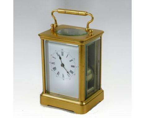 A large brass cased carriage clock, surmounted by a handle, the white enamel dial with Roman hours, having a lever platform e