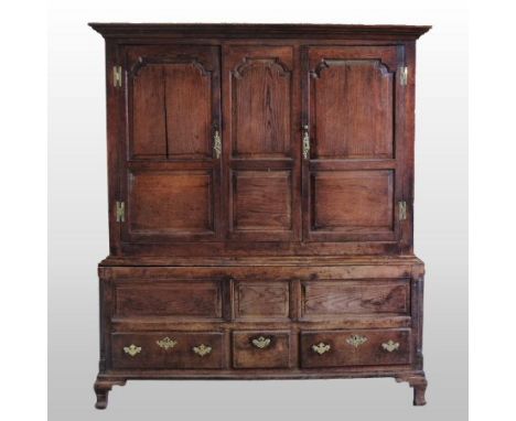 An 18th century oak Welsh hanging cupboard, the upper section with panelled doors and sides, the base containing three short 