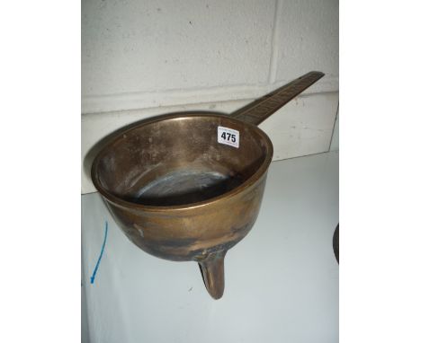 A HEAVY BRASS SAUCEPAN, on tripod feet, motif to handle