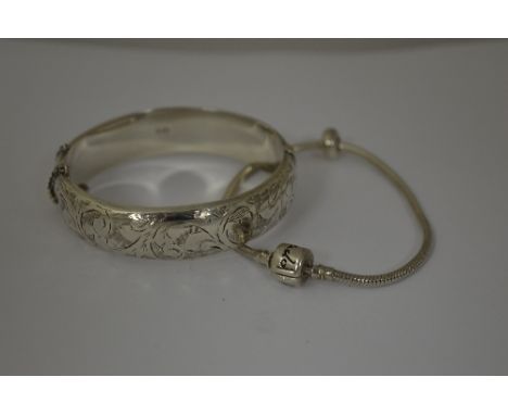 TWO BRACELETS, to include an engraved hinged bangle, together with a charm bracelet, hallmarks for London